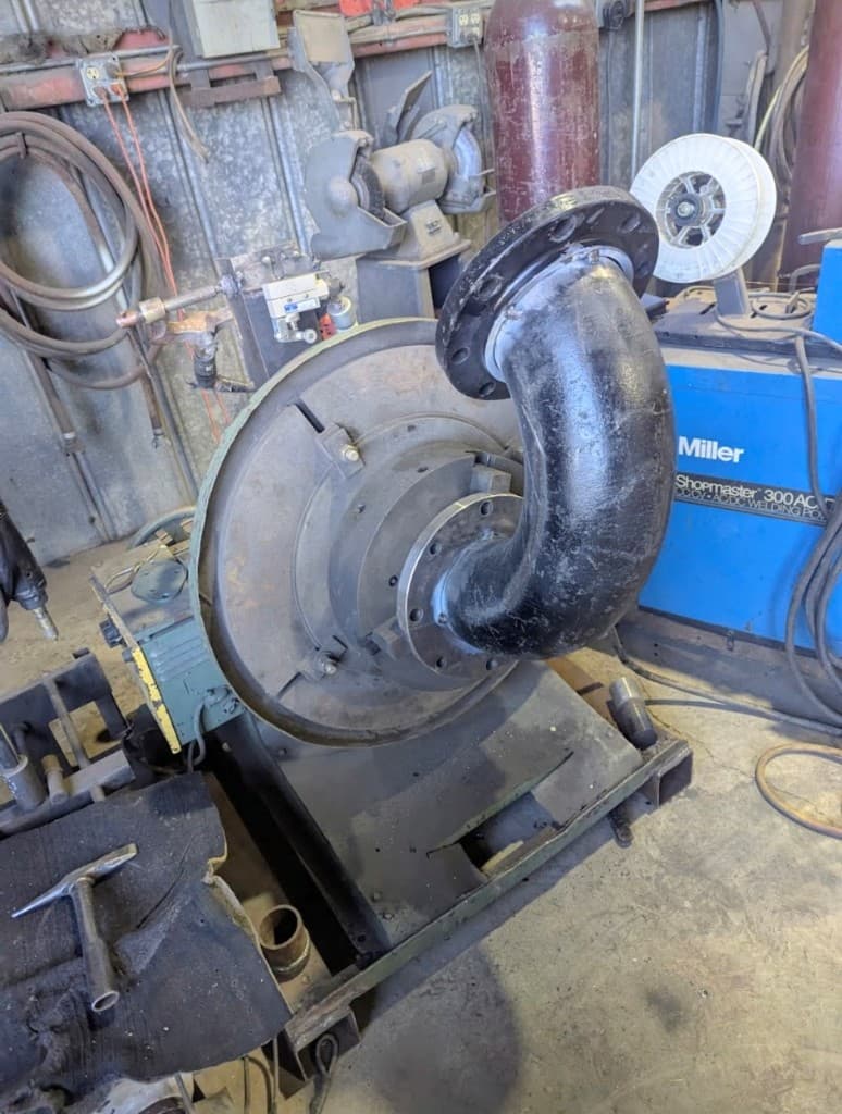 Large welded pipe elbow mounted on a welding positioner in the shop